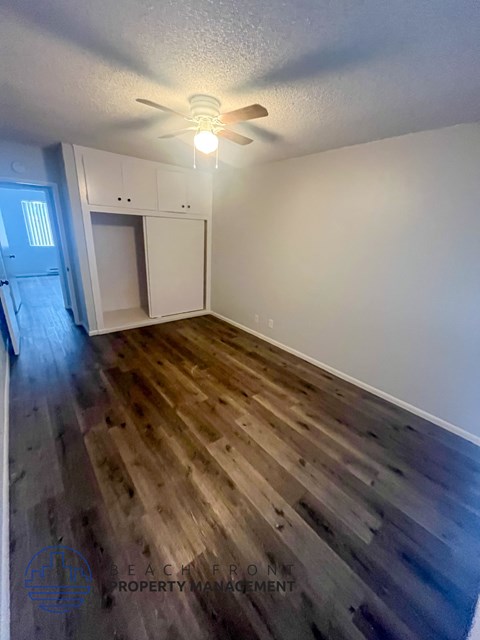 A room with a ceiling fan and wooden flooring.