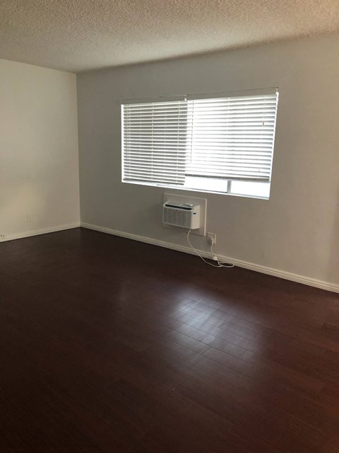 an empty living room with wood floors and a window