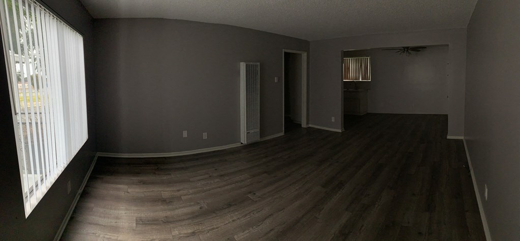 an empty living room with wood floors and a window