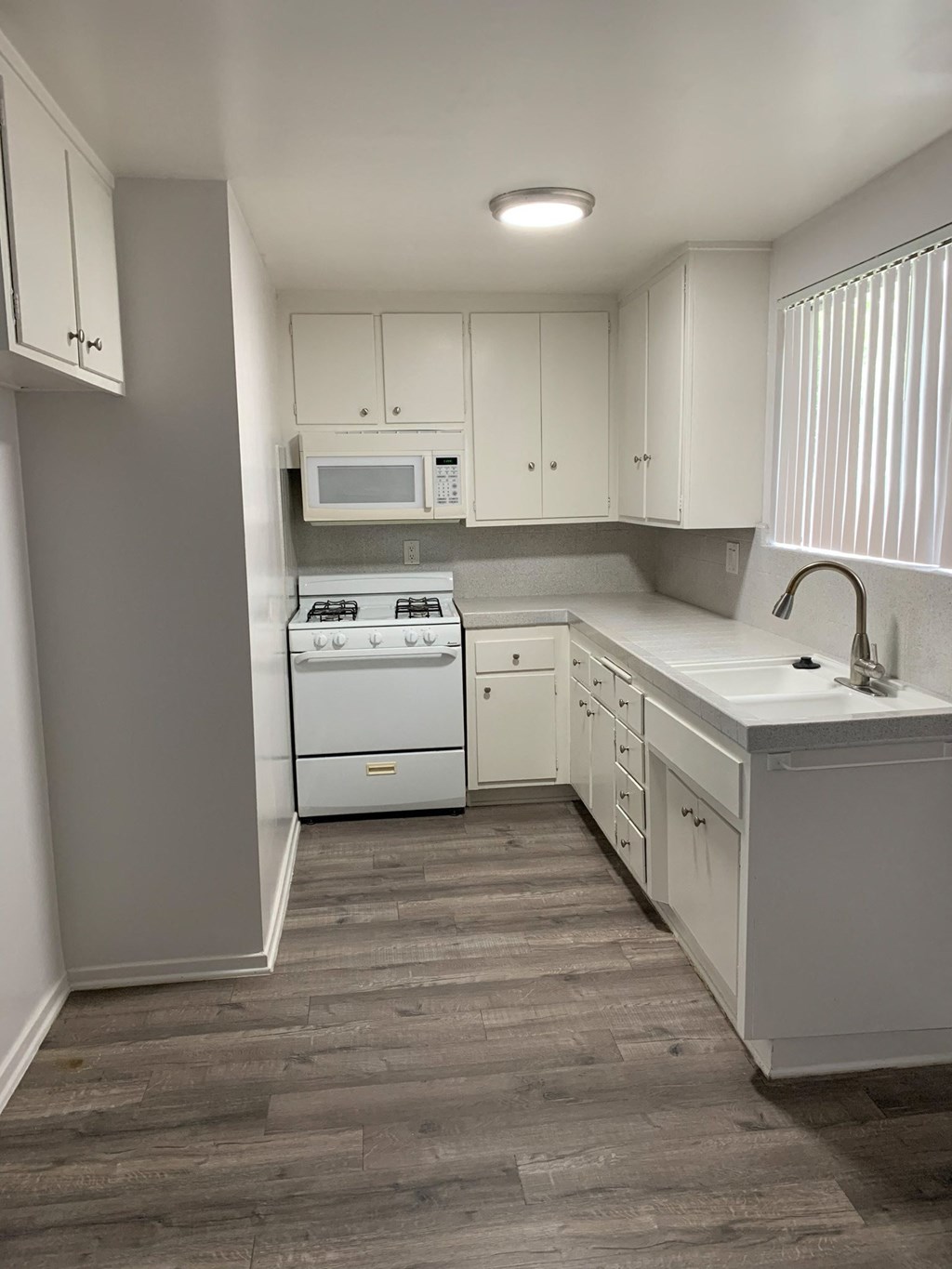 an empty kitchen with white appliances and white cabinets