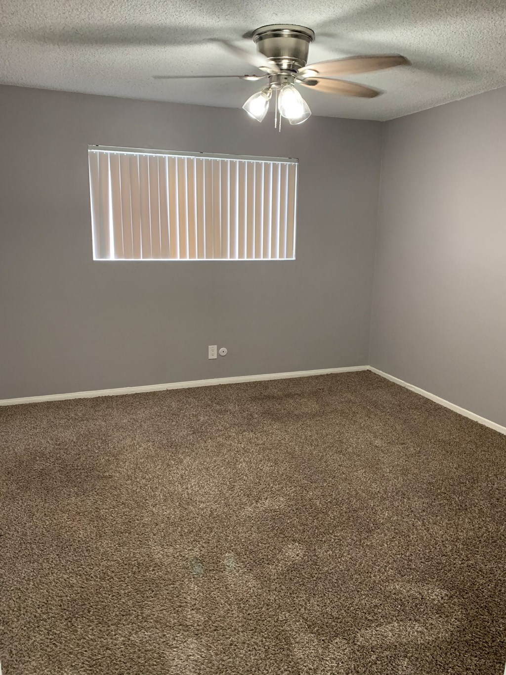 an empty room with carpet and a ceiling fan
