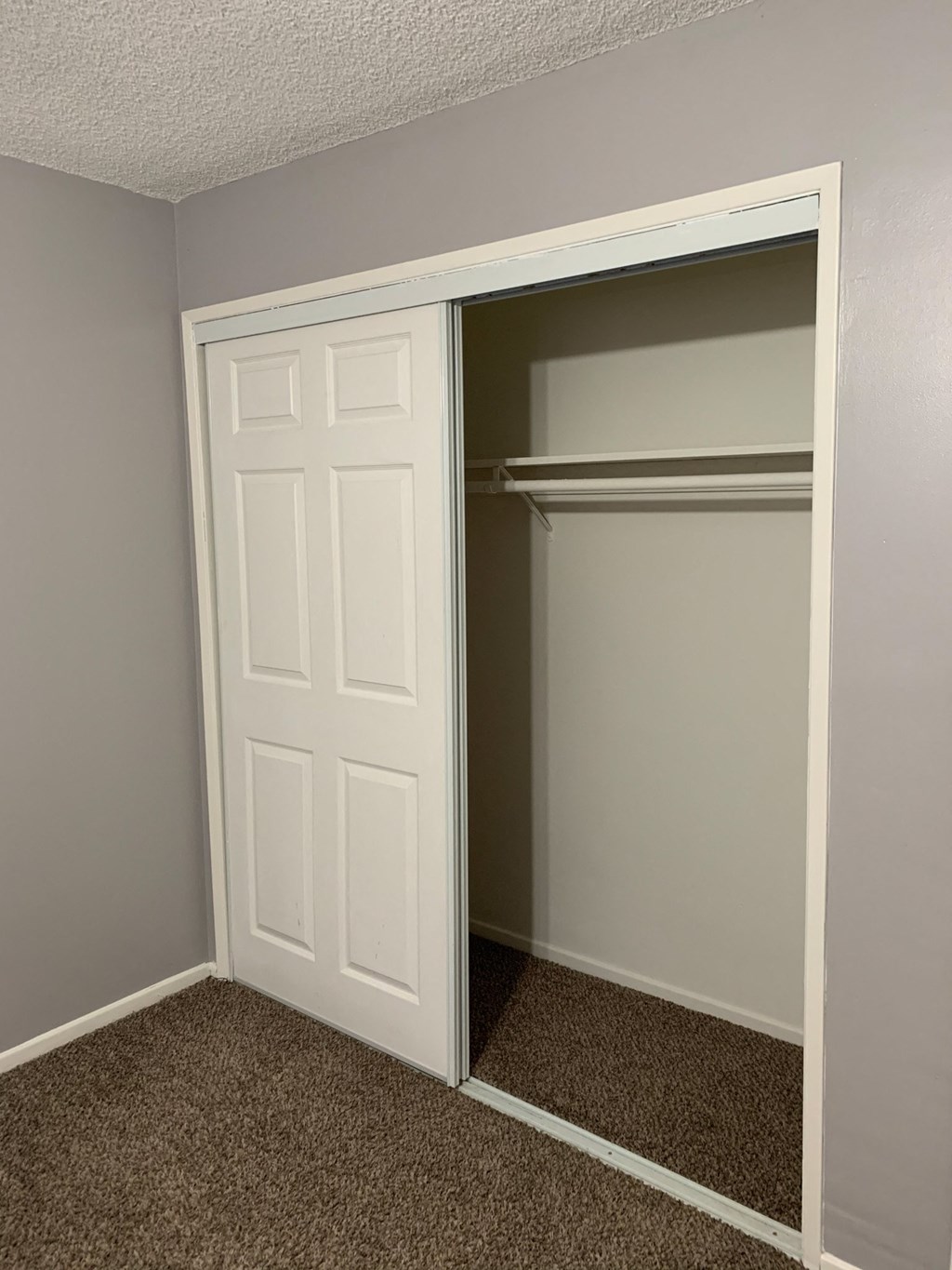 an empty bedroom with a closet and a white door