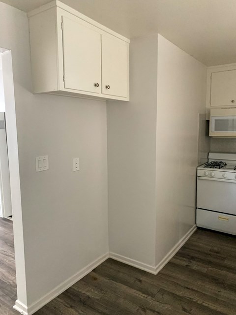 a small kitchen with white cabinets and a stove and a microwave