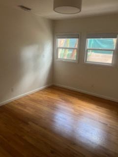 an empty room with a wooden floor and two windows