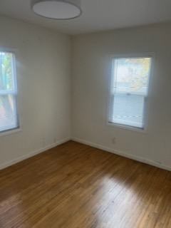 an empty room with a wooden floor and two windows
