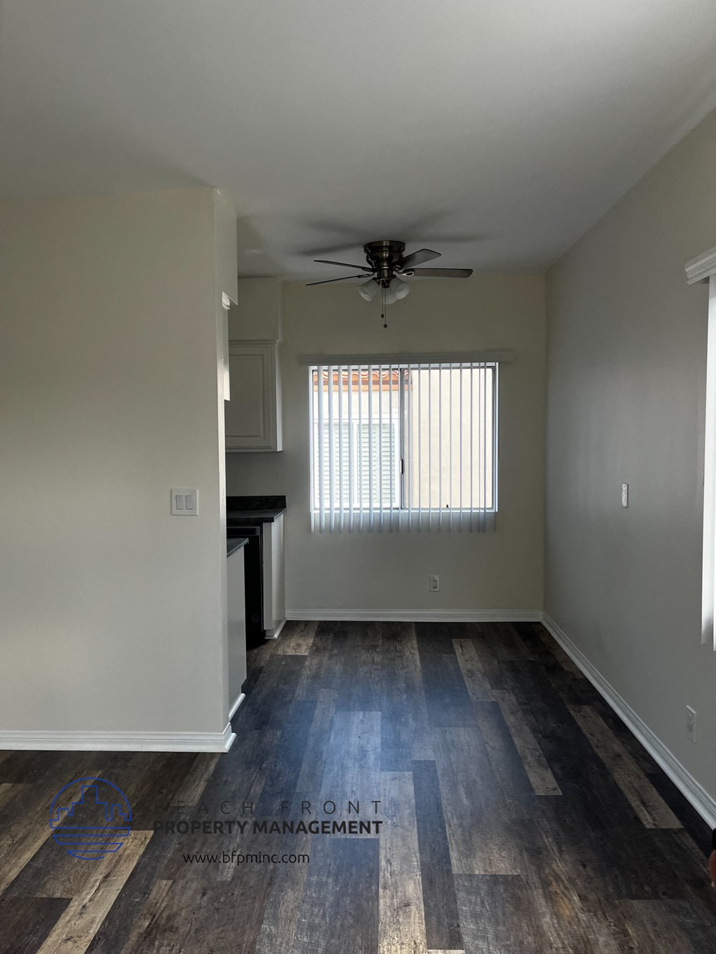 an empty living room with wood floors and a ceiling fan