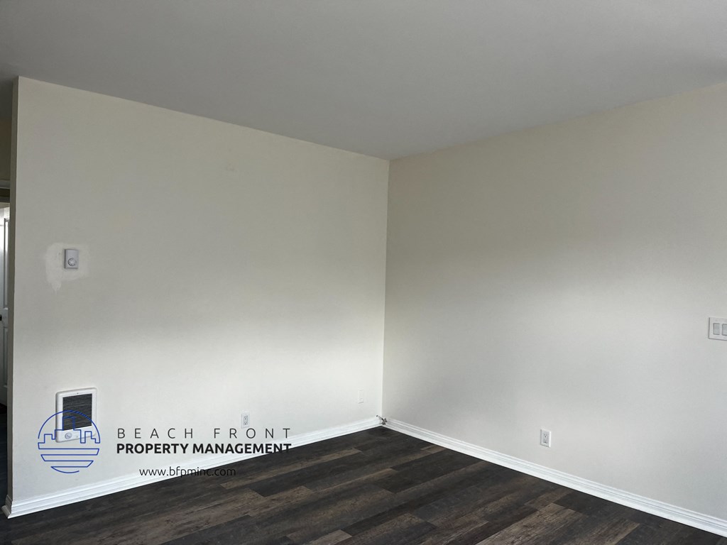 a corner of a room with white walls and wooden floors