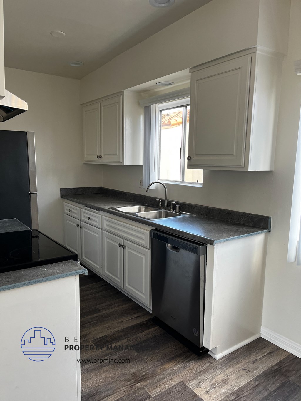 a kitchen with white cabinets and black counter tops and a sink