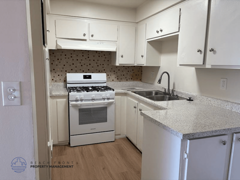 A kitchen with a stove, sink and cabinets.