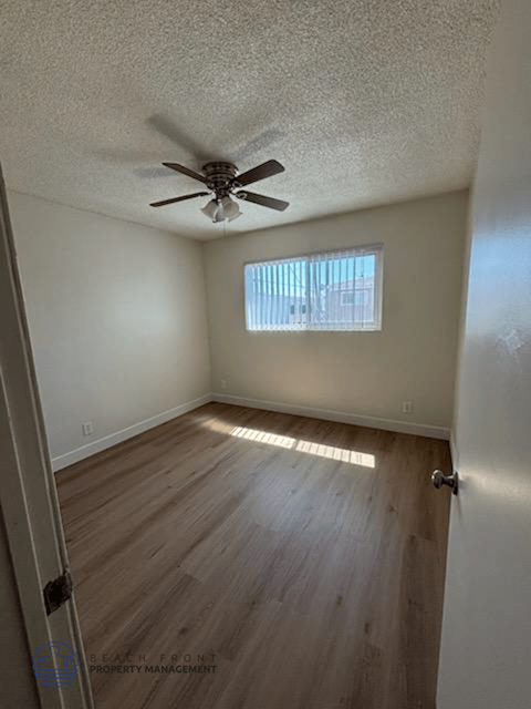 A room with a ceiling fan and wooden flooring.