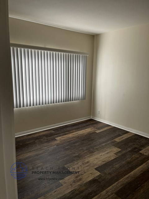 A room with wooden flooring and a window with blinds.