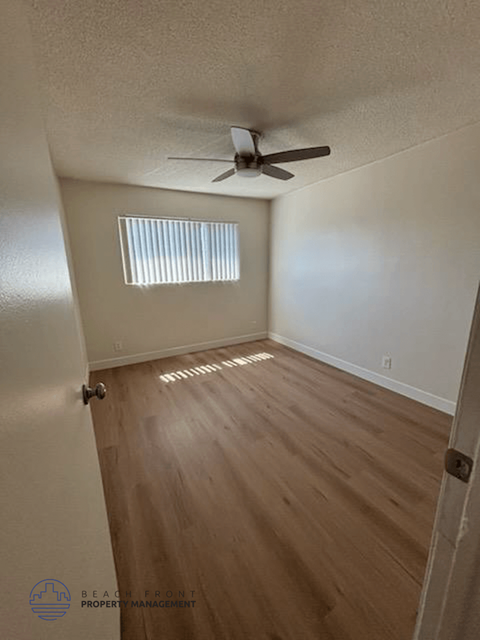 A room with a ceiling fan and wooden flooring.