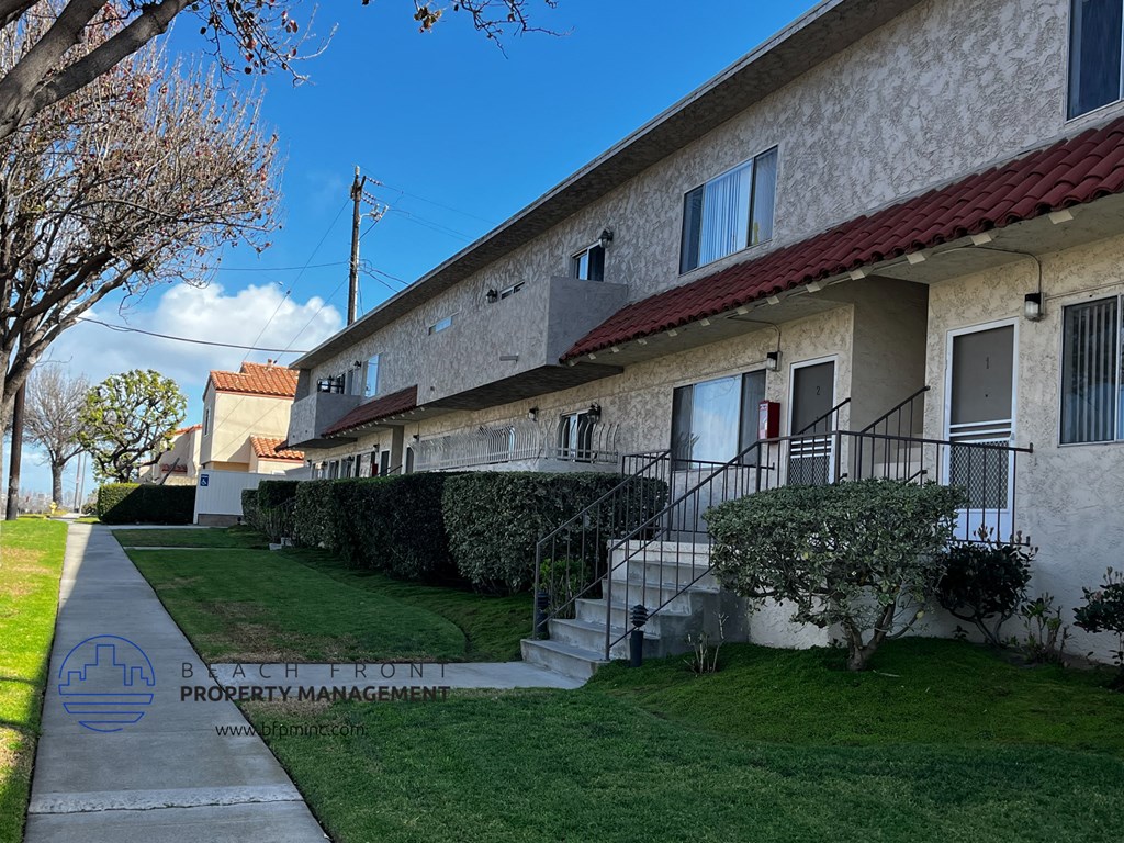 a view of the side of an apartment building with a sidewalk and grass