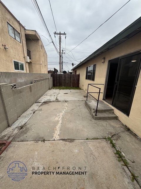 A concrete pathway leads to a building with a sign for Beachfront Property Management.