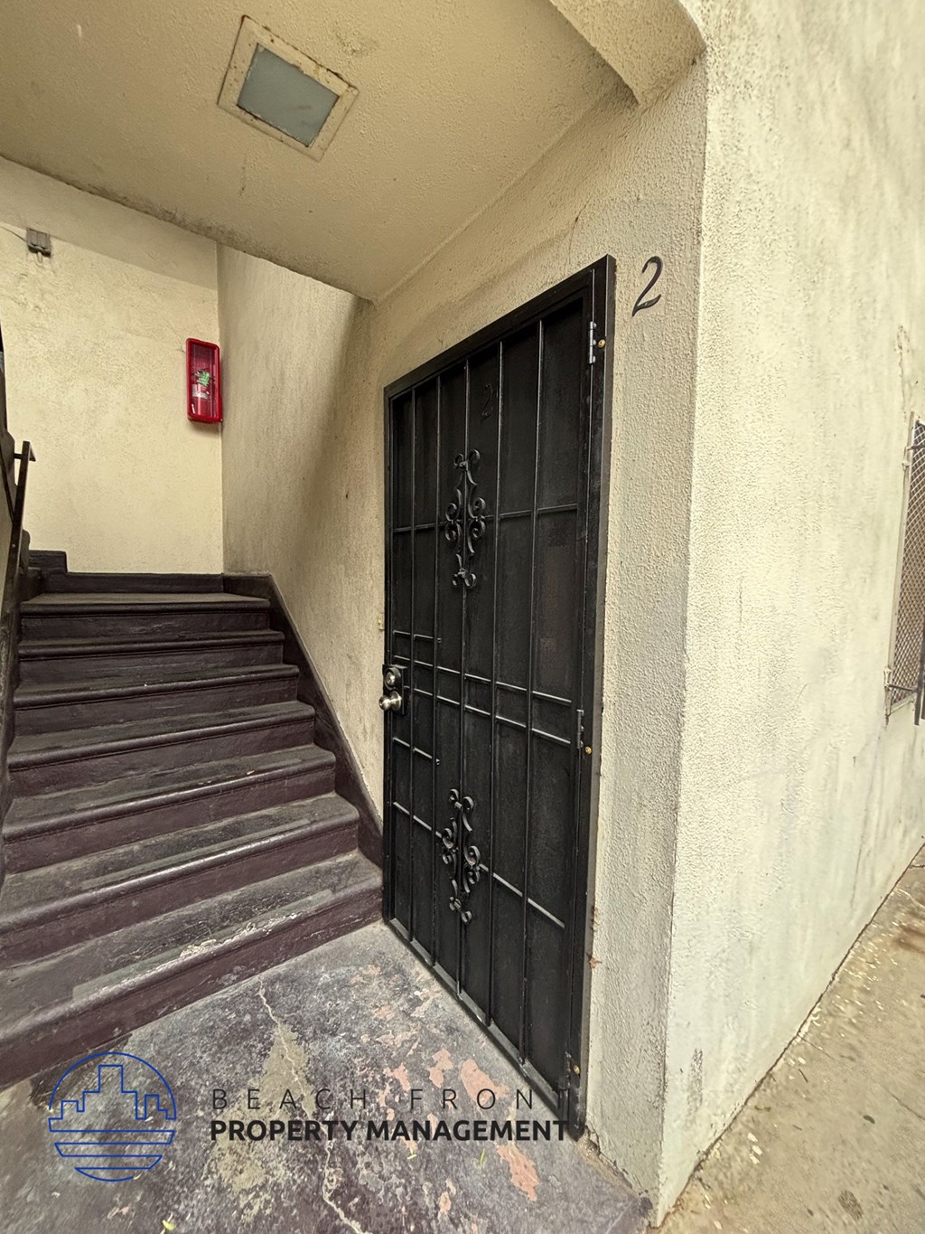 A staircase with a black door and a red fire extinguisher on the wall.