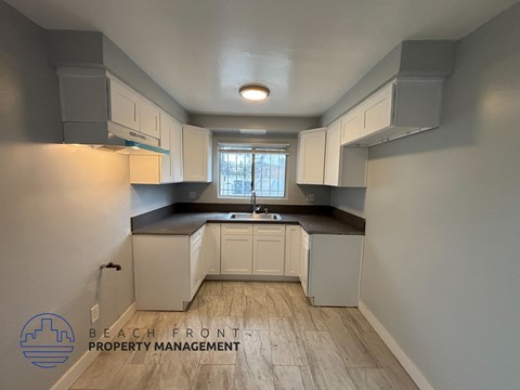 A kitchen with white cabinets and a wooden floor.