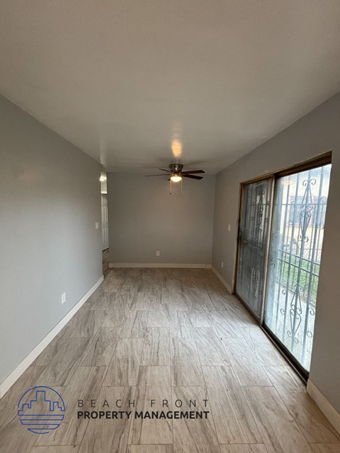 A spacious room with a ceiling fan and sliding glass doors.
