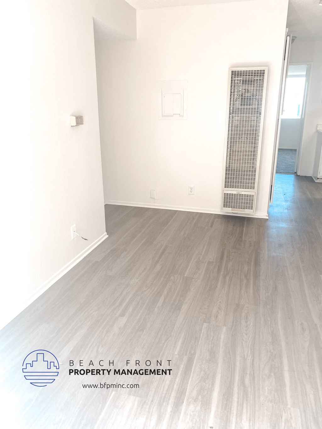 a clean white room with wood flooring and a door to a closet