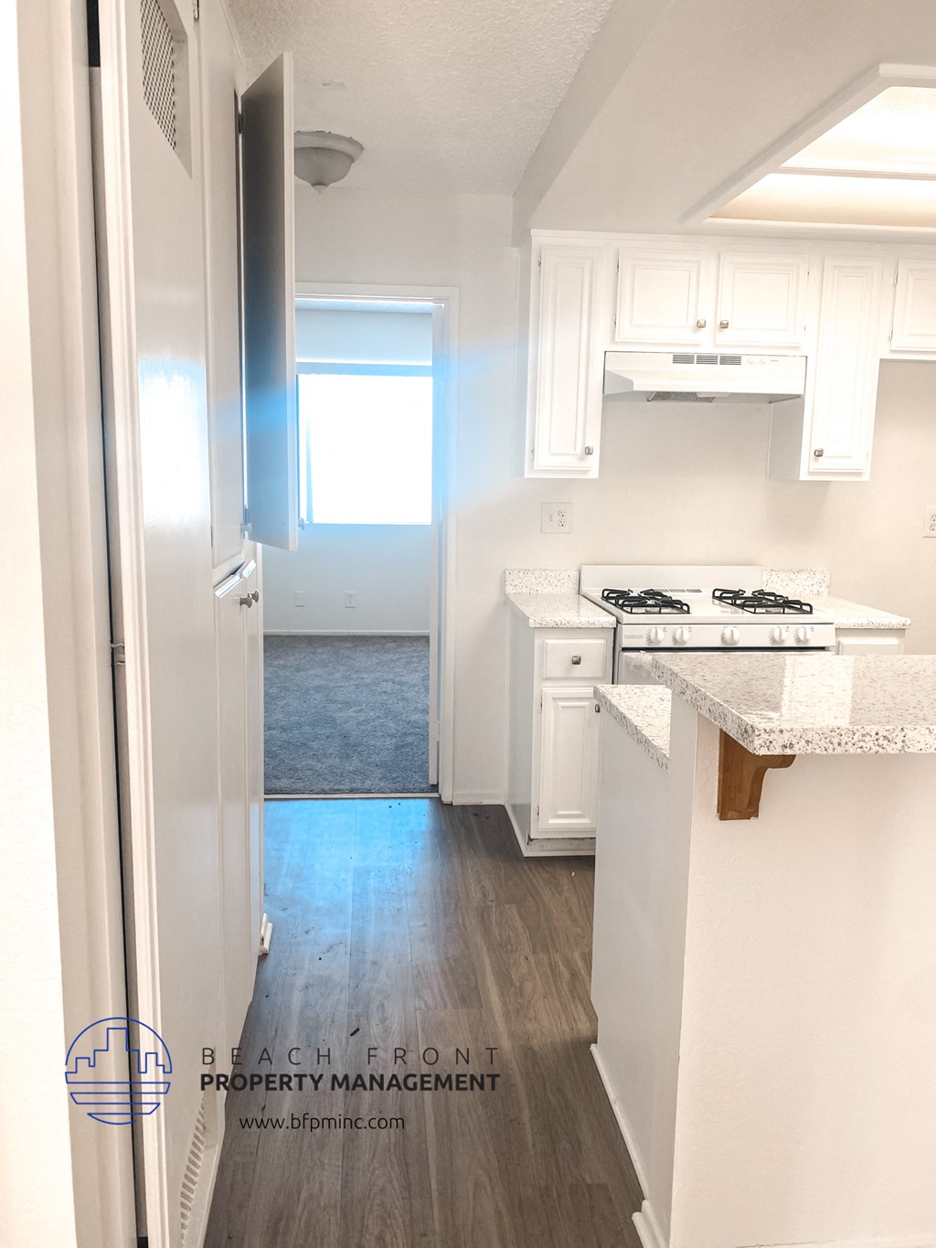 a renovated kitchen with white cabinets and white counter tops and a wood floor