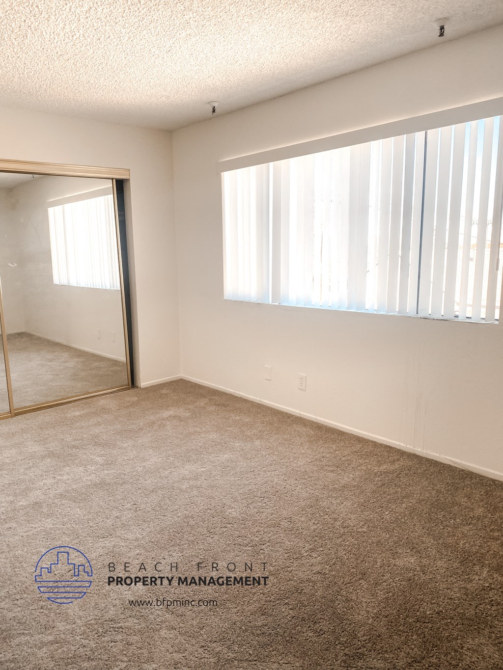 an empty living room with a large window and a mirror