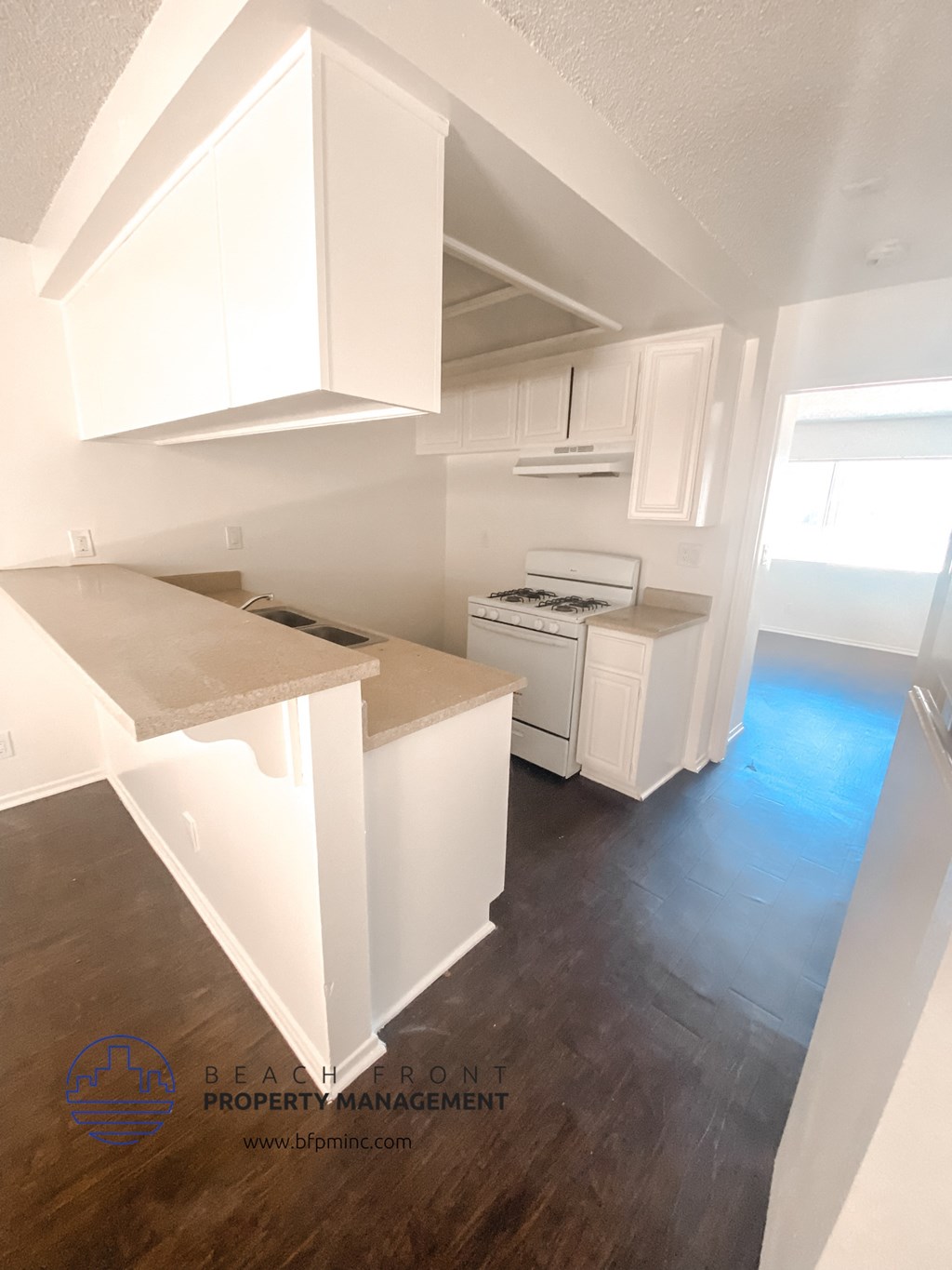 an empty kitchen with white cabinets and a wood floor