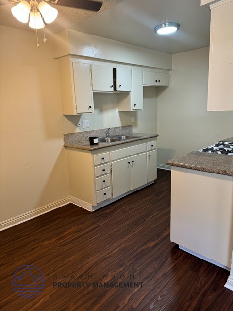 A kitchen with white cabinets and a brown floor.