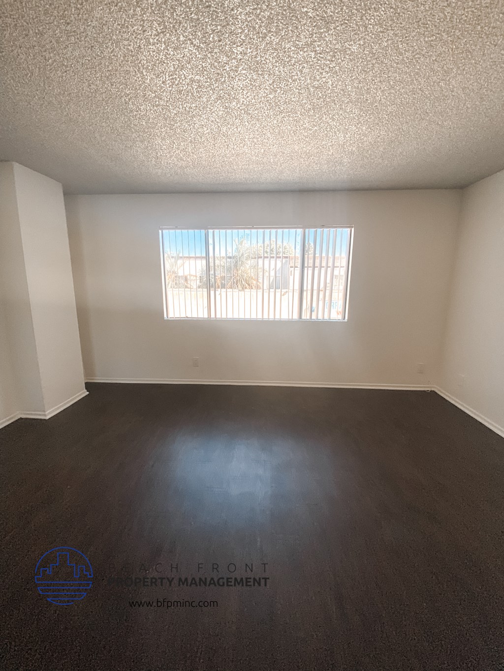 an empty living room with wood floors and a window