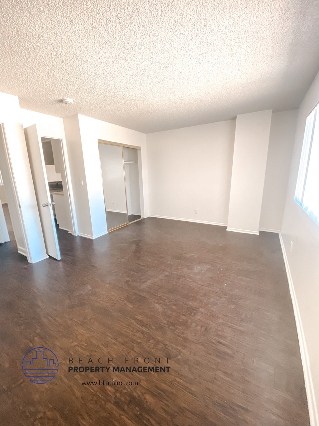 an empty living room with wood floors and white walls