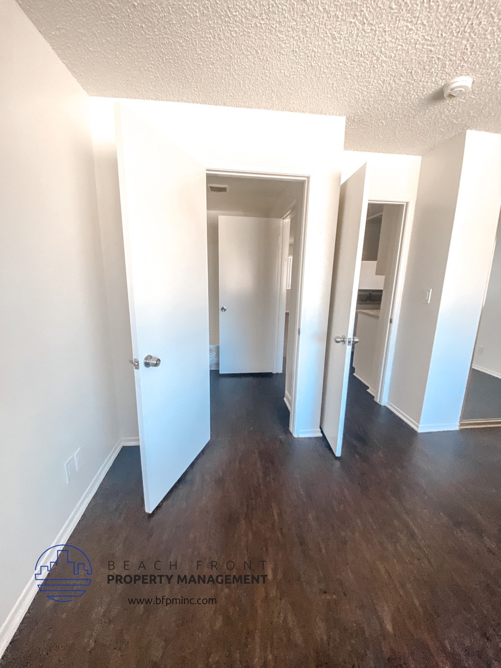 a look down the hallway of an empty room with a wood floor and white walls