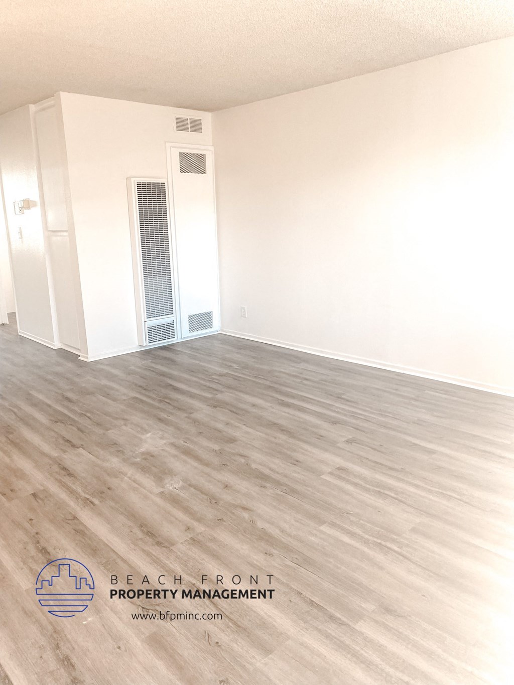 an empty room with white walls and wood flooring