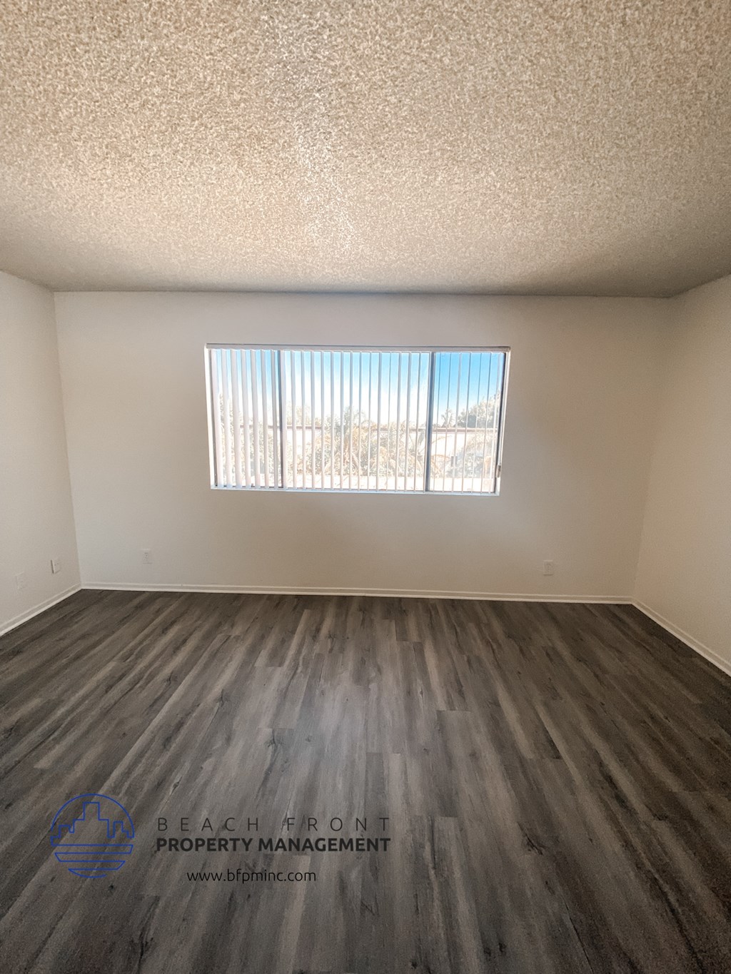 the living room of an apartment with wood flooring and a window
