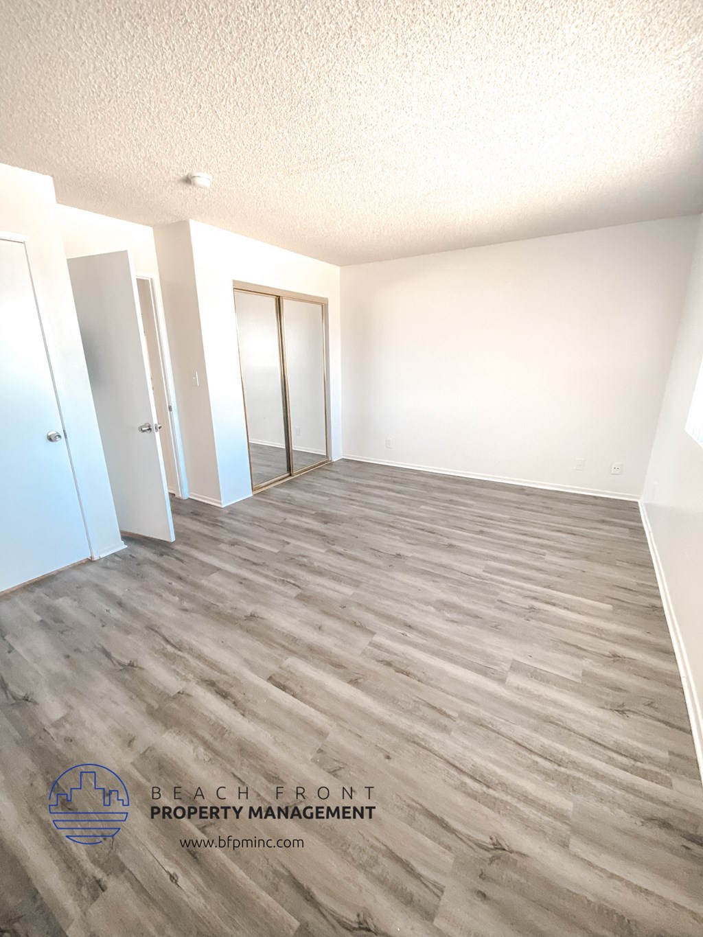 an empty room with wood flooring and white walls