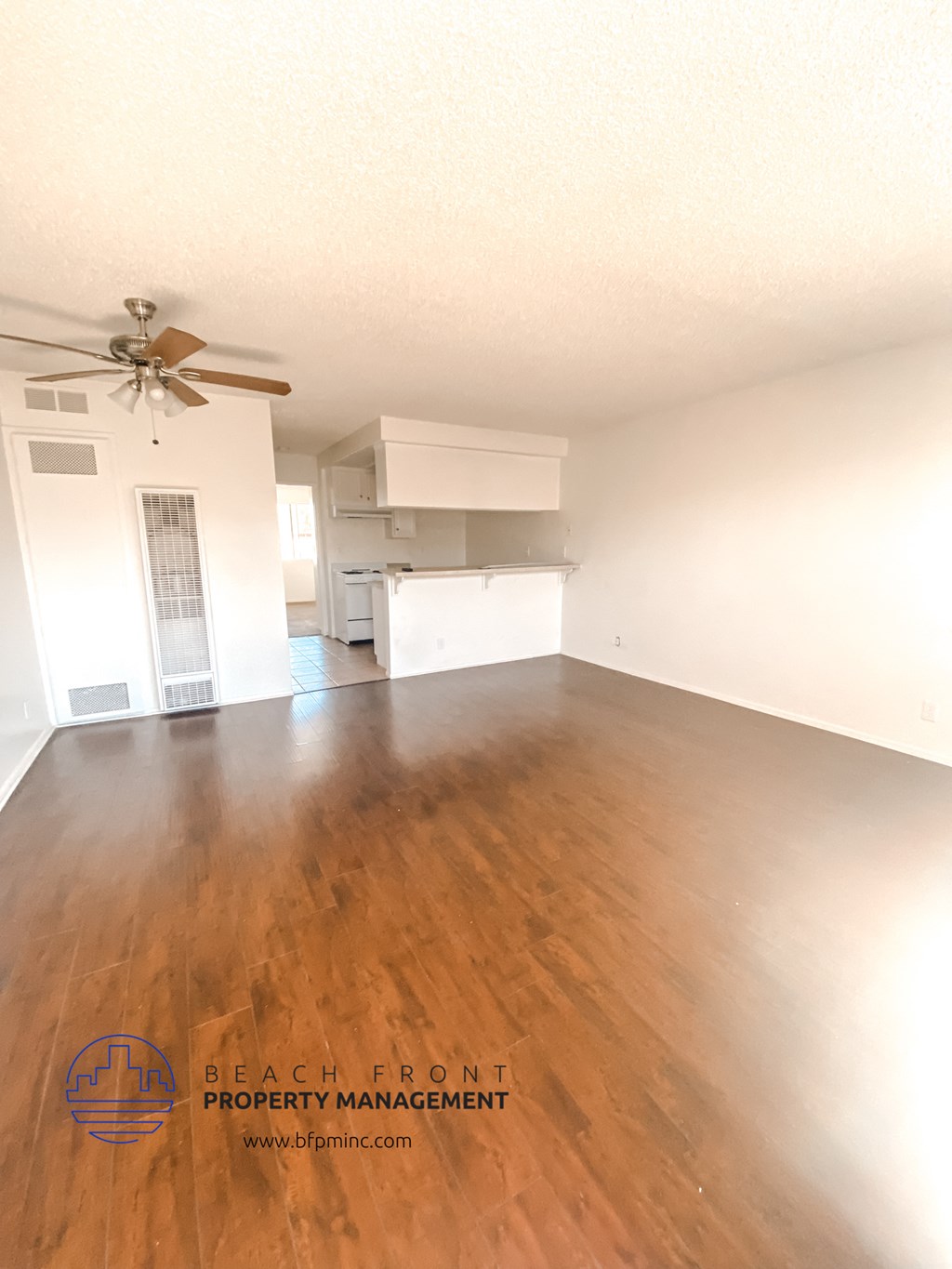 an empty living room with wood floors and a ceiling fan