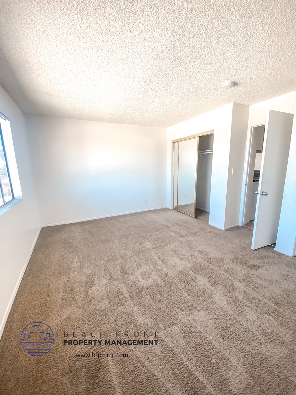the living room of an apartment with carpeting and white walls