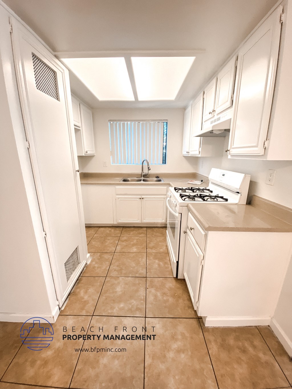 a full view of a kitchen with white cabinets and a stove and a sink