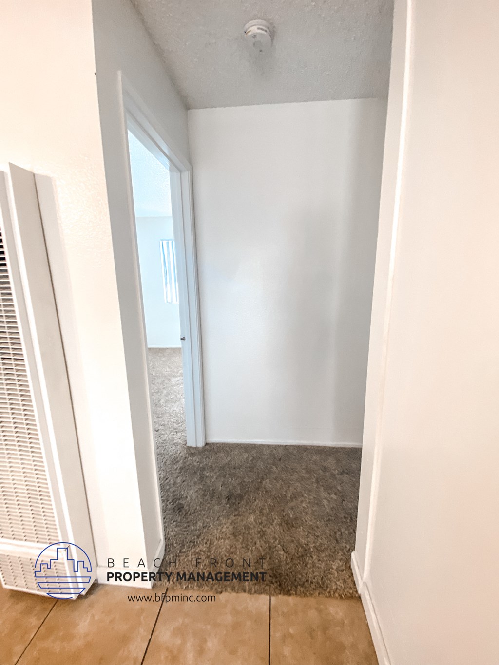 an empty room with a hallway and a door to a closet