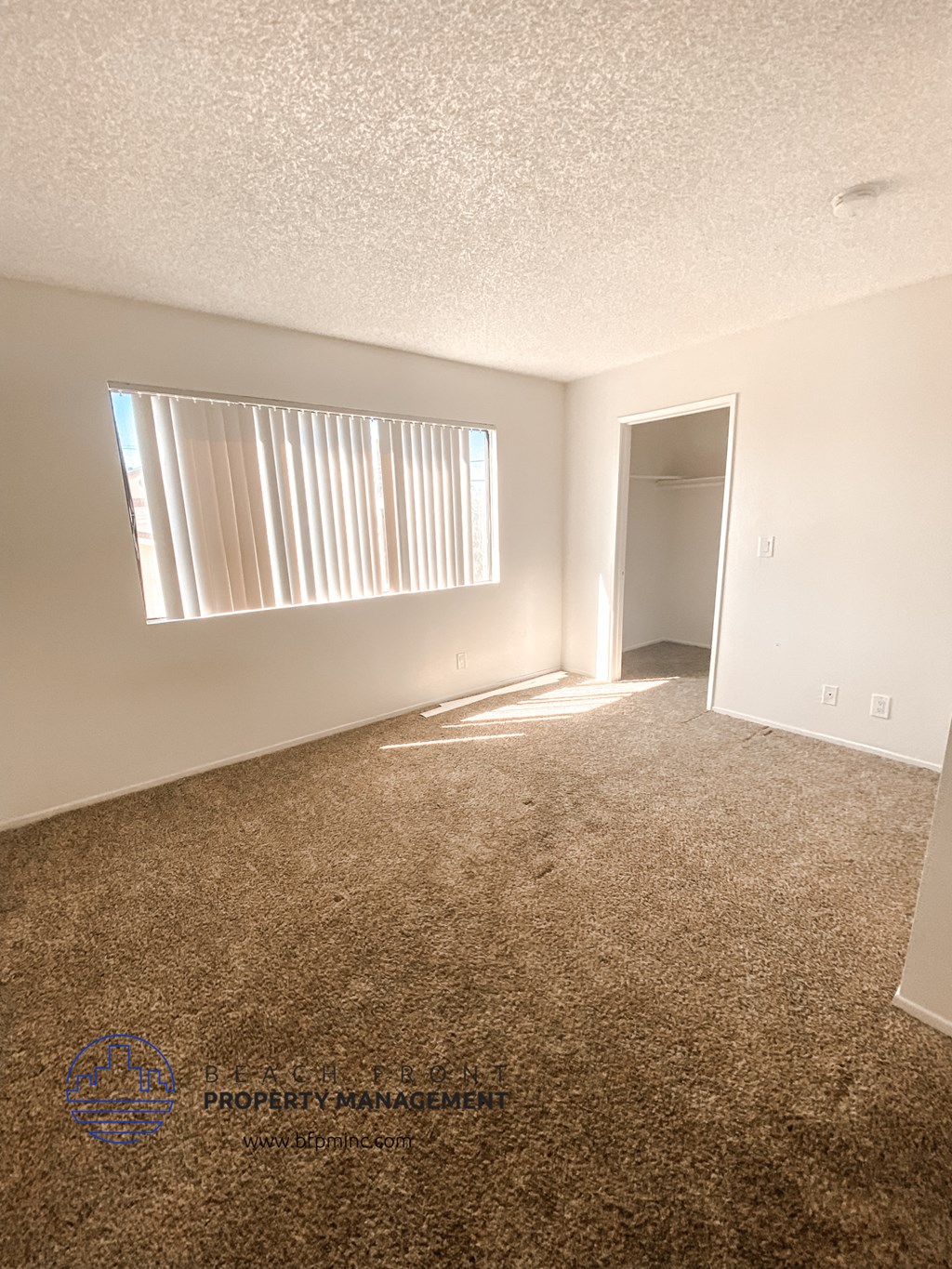 an empty living room with a window and a door to a hallway