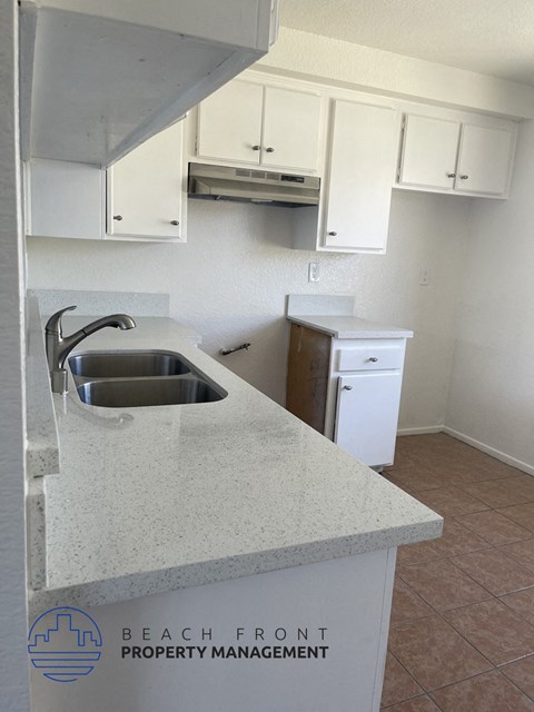 an empty kitchen with white cabinets and a sink
