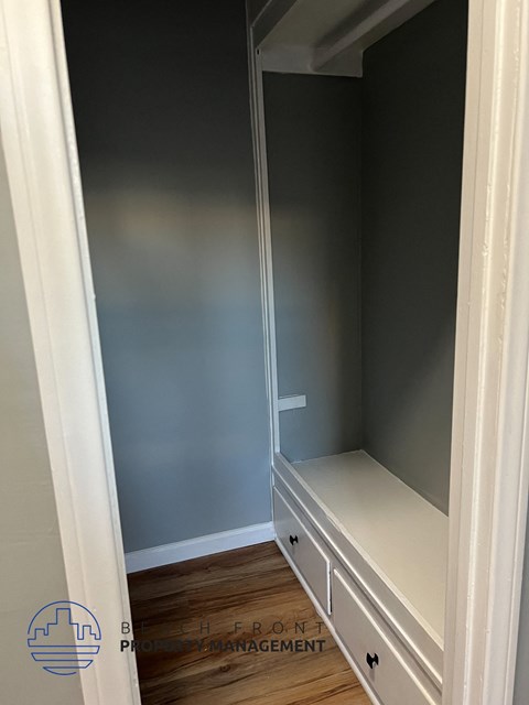 A white closet with a bench and drawers.