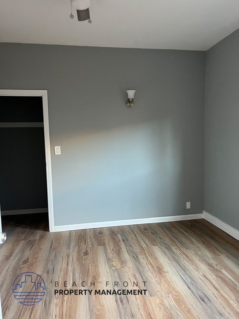 A room with wooden flooring and a grey wall.