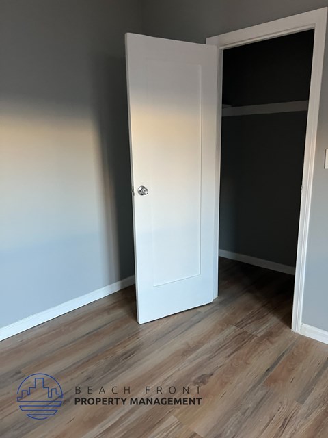 A white door is open in a room with wooden flooring.