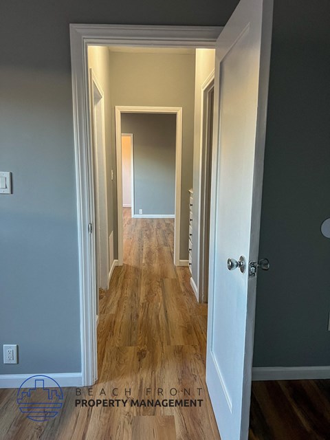 A hallway with wooden floors and white walls.