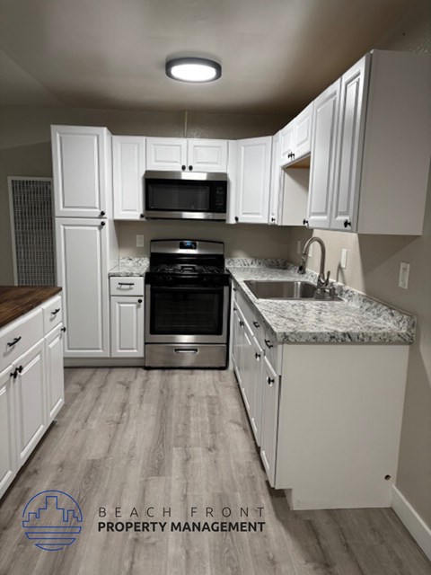 A kitchen with white cabinets and a granite countertop.