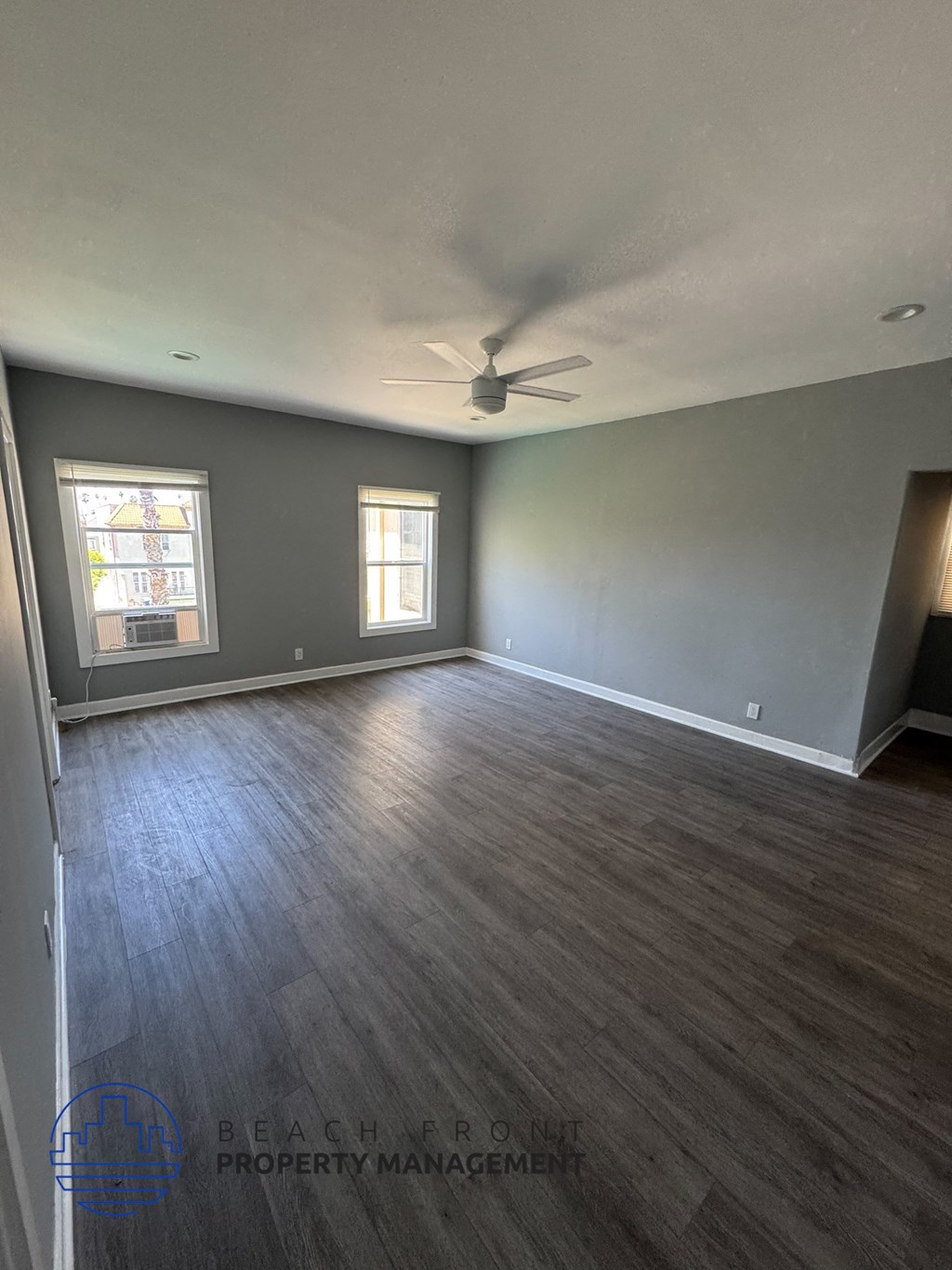 A spacious room with wooden flooring and a ceiling fan.