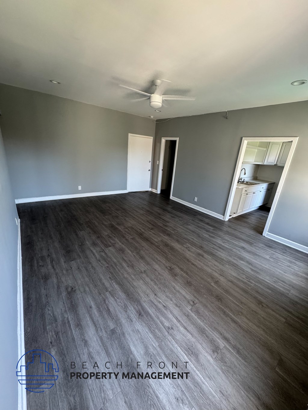A spacious room with wooden flooring and a ceiling fan.