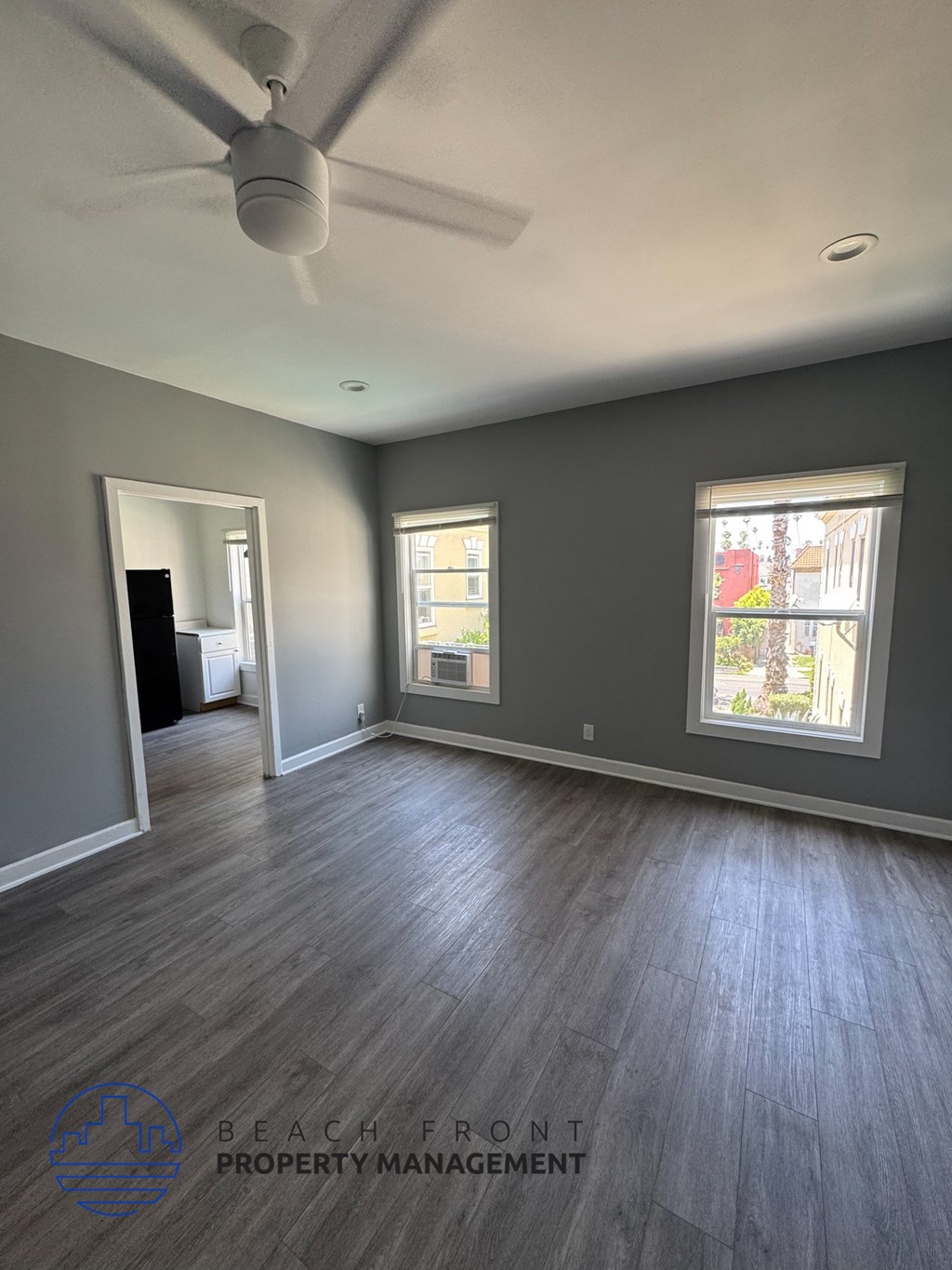 A spacious room with a ceiling fan and hardwood flooring.