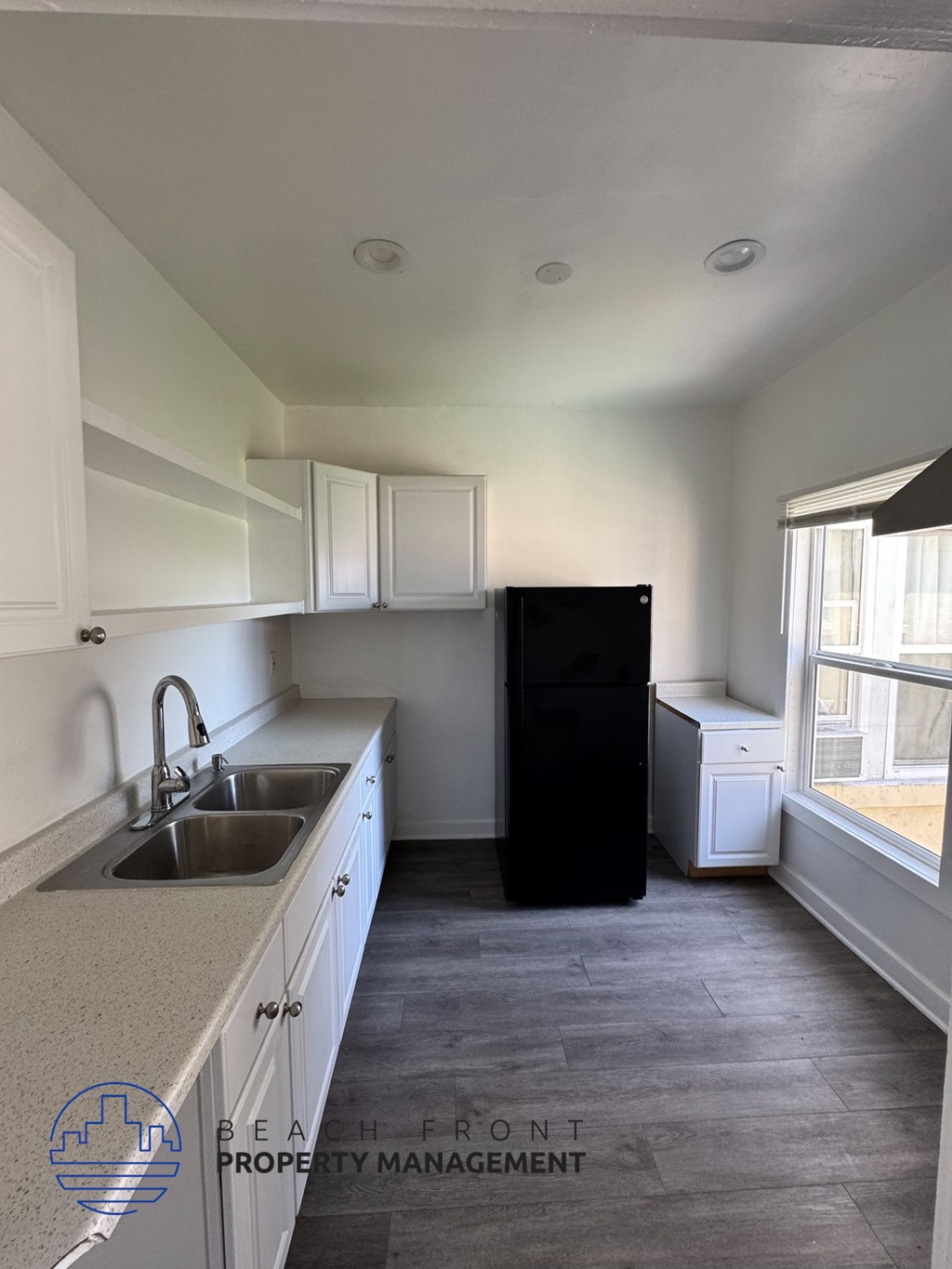 A kitchen with a sink, a refrigerator, and a window.