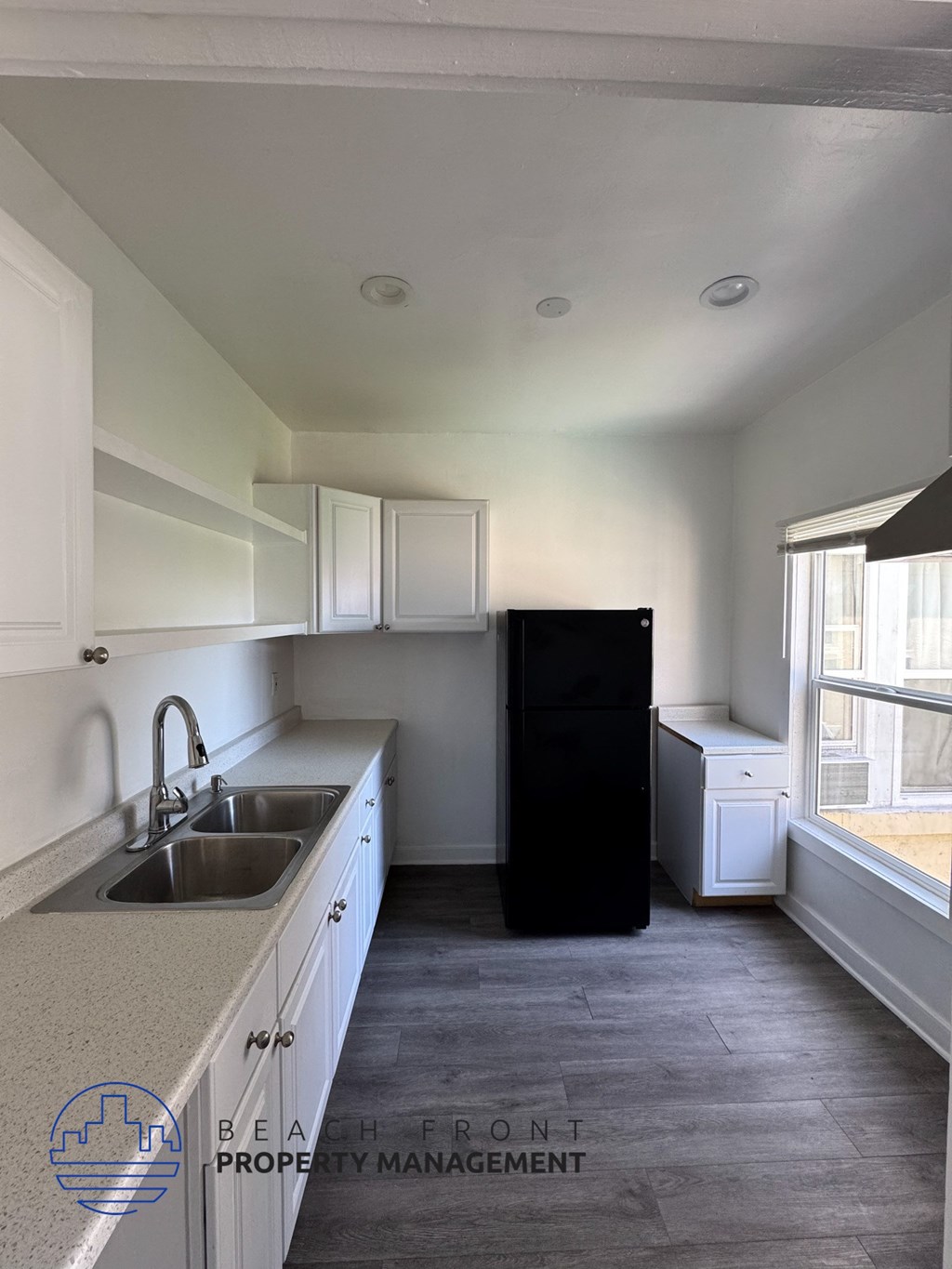 A kitchen with a sink, a refrigerator, and a window.