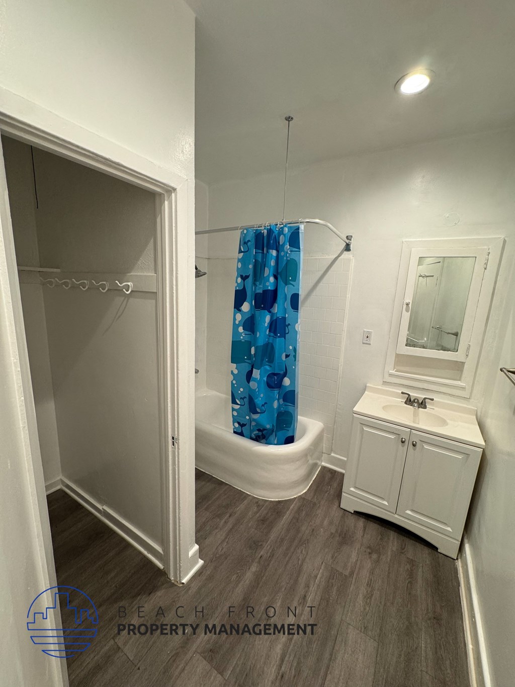 A bathroom with a blue shower curtain and a white cabinet.