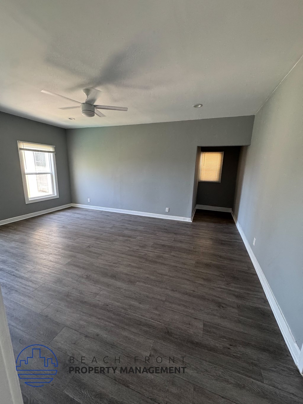 A room with a ceiling fan and wooden flooring.